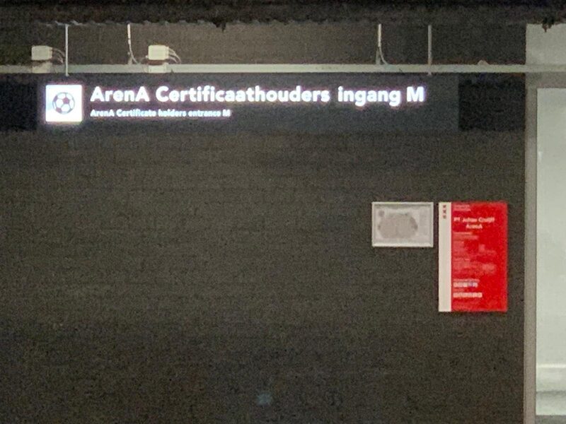 The illuminated ArenA Certificate holders entrance M sign at night